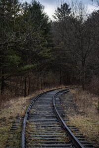 Abandoned railway tracks winding through a dense forest in Ontario, Canada during late fall.